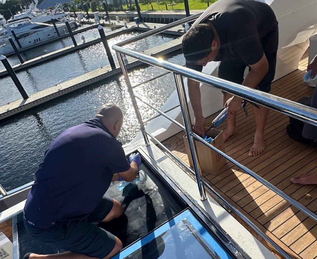 Boatique technicians installing a glass deck panel on a yacht